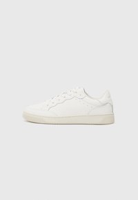Hvite lær sneakers med perforerte detaljer, tonale snørebånd og en teksturert gummisåle. Har en subtil kontrastfarge på hælen.