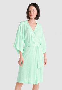 Bata corta de estilo kimono en verde menta, con mangas anchas, cinturón en la cintura y un sutil patrón de lunares en tela suave.