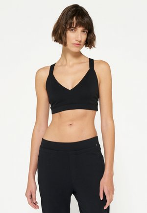 Zwarte sportbh met een V-hals ontwerp, brede schouderbanden en een naadloze band. Gladde textuur, minimalistische stijl, past goed bij zwarte broek.