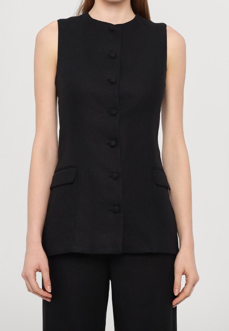 Černá bezrukávová vesta z lnu, s vysokým límcem, zapínáním na pět knoflíků a dvěma předními kapsami s patkami.