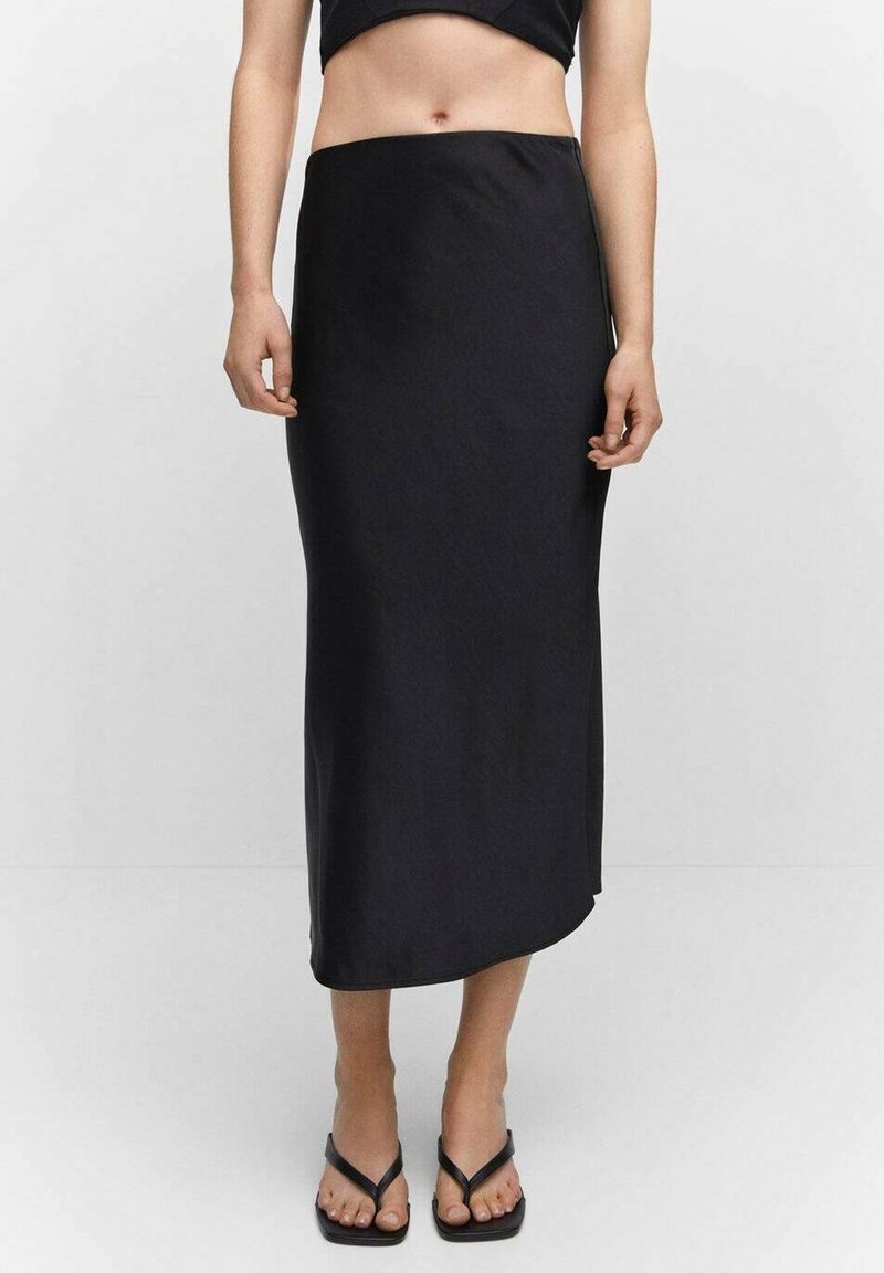 Schwarze Satin-Maxi-Rock mit einer eleganten, glatten Textur, der eine gerade Silhouette und einen dezenten Seitenschlitz aufweist. Getragen mit schwarzen Flip-Flops.