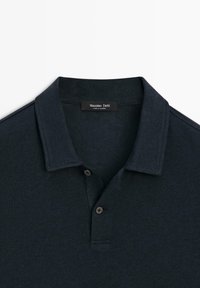 Polo bleu marine foncé avec col plié et deux boutons, affichant l'étiquette de la marque Massimo Dutti à l’intérieur du col.