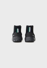 Botas negras de tobillo con parte superior de ante, que presentan un acento de rayas verdes, blancas y negras en la parte posterior y una suela de goma duradera.