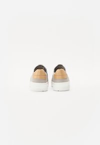 Grå lær-sneakers med tan detaljer, hvite gummisåler og en glatt tekstur. Har en drakrok ved hælen og et minimalistisk design.
