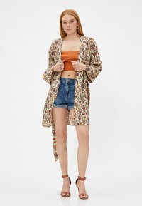 Kimono w kwiatowym wzorze wykonane z lekkiego materiału, z szerokimi rękawami, otwartym przodem i swobodnym krojem. Noszone na krótki top i szorty.