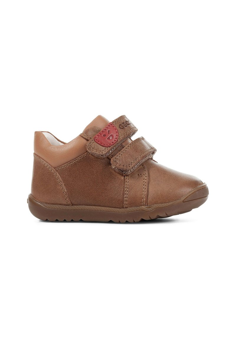 Scarpe per bambini in pelle marrone con due cinturini in velcro, punta rotonda, superficie testurizzata e suola in gomma. Accento rosso sul cinturino.