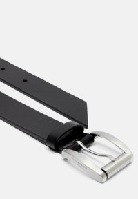 Czarny skórzany pasek o gładkiej fakturze, zwężającym się końcu i błyszczącej srebrnej klamrze z wygrawerowanym detalem marki.