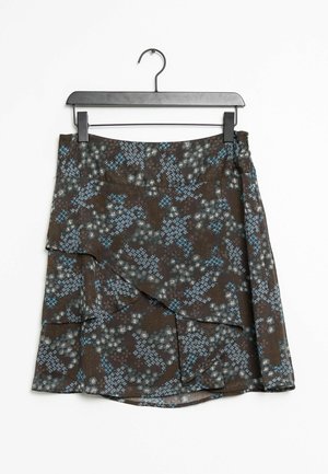 Jupe portefeuille marron à motifs floraux bleus et blancs suspendue sur un cintre en plastique noir sur fond blanc.