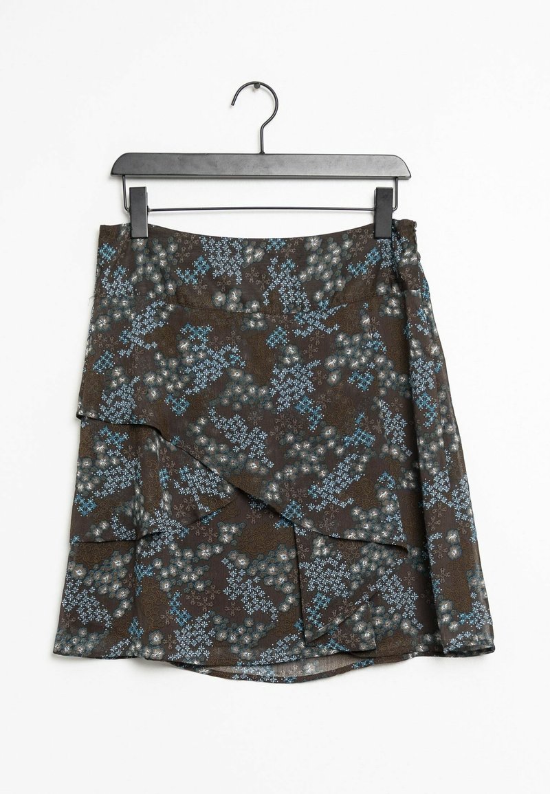 Jupe portefeuille marron à motifs floraux bleus et blancs suspendue sur un cintre en plastique noir sur fond blanc.