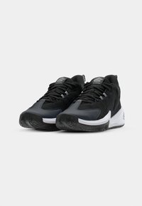 Black athletic shoes featuring a combination of mesh and synthetic materials, a white midsole, and textured rubber outsoles with intricate patterns.