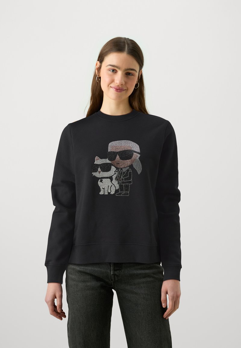 Sudadera negra con un gráfico adornado con pedrería de un personaje y un gato, ambos con gafas de sol. Cuello redondo, mangas largas, corte relajado.