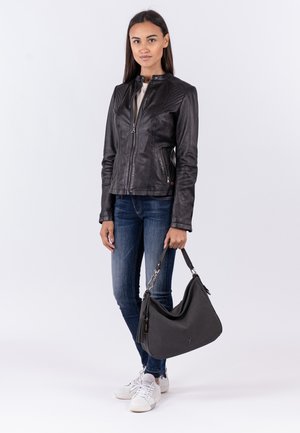 Veste en cuir noir avec un col montant, épaules texturées, fermeture éclair, associée à un jean en denim foncé et un sac à main noir décontracté.