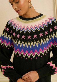 Pulover negru tricotat cu un model geometric colorat, având zig-zaguri și stele în nuanțe de roz, albastru și auriu. Gât rotund și mâneci lungi.