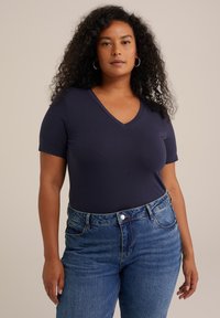 Camiseta de manga corta en color azul marino con escote en V, hecha de una tela suave, combinada con jeans de mezclilla de tiro alto en un tono azul claro que presentan un diseño clásico de cinco bolsillos.