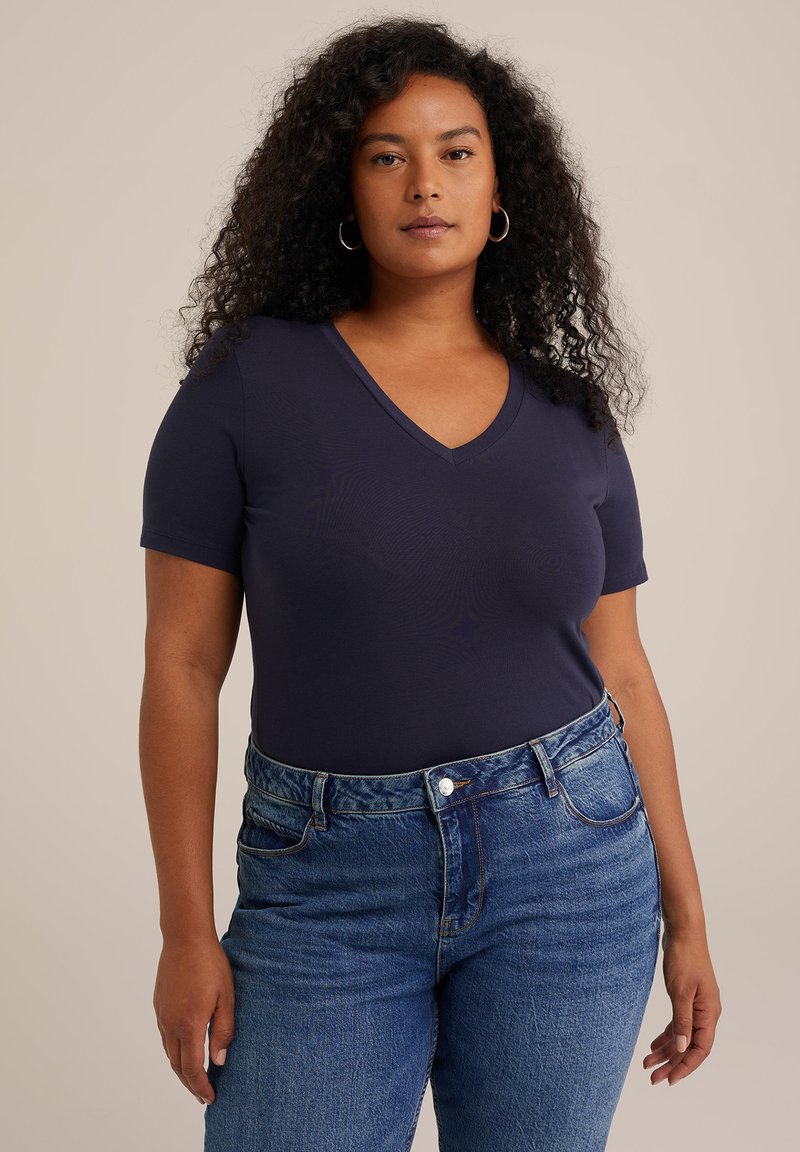 Camiseta de manga corta en color azul marino con escote en V, hecha de una tela suave, combinada con jeans de mezclilla de tiro alto en un tono azul claro que presentan un diseño clásico de cinco bolsillos.