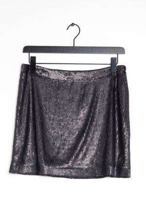 Jupe noire à sequins suspendue sur un cintre noir sur un fond blanc.