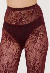 Burgundy spetstövlar med blommönster, som har en genomskinlig design och ett elastiskt midjeband för komfort och passform.