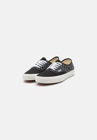 Sorte og hvite sjakkbrikker-sneakers med canvas-overdel, hvite snøringer og hvit gummisåle. Klassisk lavt design med tekstilstruktur.