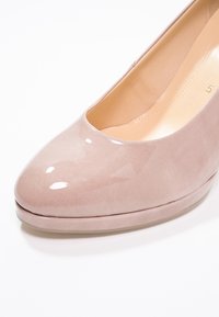 Chaussure à talons hauts en cuir verni beige avec bout arrondi et semelle intérieure rembourrée, taille 5 visible à l'intérieur.