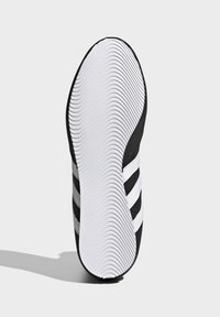 Mustan ja valkoisen urheiluvaatteen pohja, jossa on teksturoitu kumipinta pidon lisäämiseksi, kolmella valkoisella raidalla sivulla ja kaarevalla, sileällä reunalla.