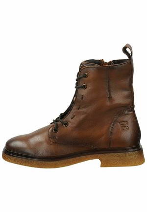 Brauner Lederknöchelschuh mit runder Zehenpartie, Schnürung vorne und kleinem Ziehschlauf. Strukturierte Gummisohle mit dezentem Branding an der Seite.