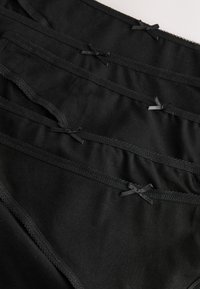 Czarne bawełniane majtki z satynowymi kokardkami na pasku. Charakteryzują się gładką fakturą i zaokrąglonymi krawędziami, wykonane w klasycznym kroju.