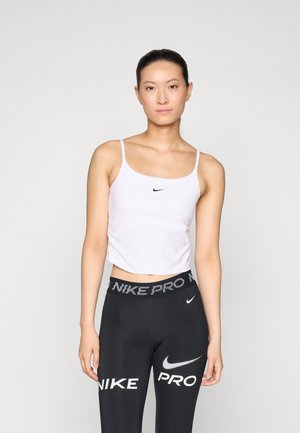 Fehér, cropped tank top vékony pántokkal, a bal oldalon egy kis fekete Nike logóval. Fekete leggings-szel párosítva, amelyen a derékrészen a "NIKE PRO" felirat látható.