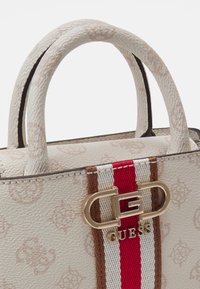 Sac à main texturé blanc avec un accent à rayures marron et rouge. Il dispose de deux poignées courtes et d'un fermoir en or avec logo. Extérieur à motif.