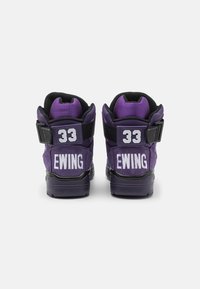 Fialové vysoké tenisky s černými detaily, s tlustou podrážkou, polstrovaným límcem a bílými nápisy "33" a "EWING" na zadní straně.