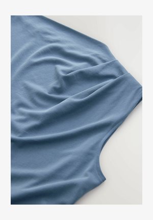 Maglietta blu vista dall'alto, con un tessuto morbido e una superficie liscia, pieghe cadenti e un collo rotondo.