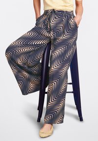 Brede broek met een marineblauw en beige zigzagpatroon, gemaakt van een lichtgewicht stof, met een elastische tailleband en zijzakken voor functionaliteit.