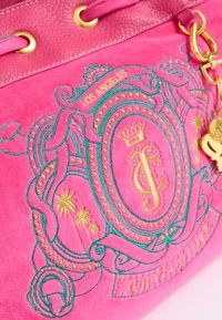 Borsa in suede rosa con dettagli dorati, ricamo verde, caratterizzata da un design con stemma e testo "Los Angeles", oltre a borchie decorative.