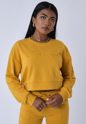 Geel cropped sweatshirt met geborduurde tekst "Project x Paris". Glad textuur, lange mouwen en een comfortabele fit, gecombineerd met bijpassende broek.