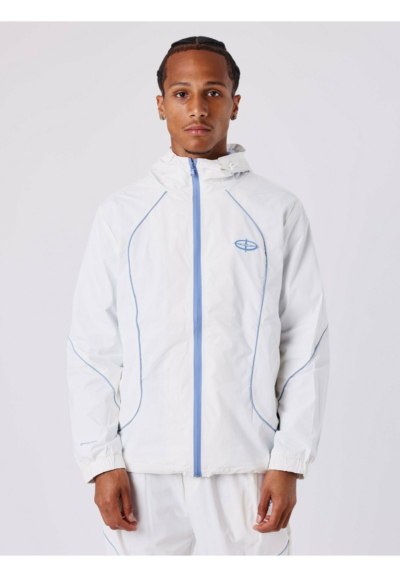Witte lichtgewicht jas met een blauwe rits en stiksels. Voorzien van een capuchon en elastische manchetten, met een subtiele logo op de borst.