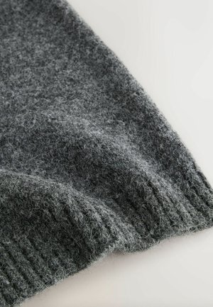 Grå strikket sweaterstof med en blød tekstur og ribbet kant, der viser varierende nuancer af grå med fine, fuzzy fibre.