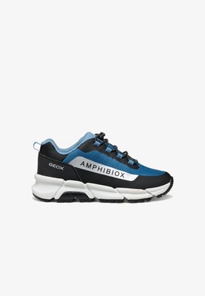 Chaussure de sport avec une combinaison de couleurs noire, bleue et blanche ; présente un logo, un tissu texturé et une semelle durable avec des crampons proéminents pour une meilleure adhérence.