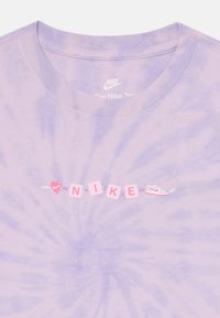 Lilla sidemusteriga T-särk ümmarguse kaelusega, millel on sõna "NIKE" roosa värviga plokkidena, millele on lisatud südame ja tennisekinga graafika.
