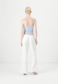 Top strapless albastru deschis, ajustat, asortat cu pantaloni albi cu picioare late, având o talie elastică; design minimalistic, textură netedă.
