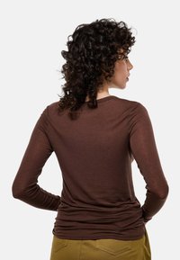 Haut marron à manches longues avec une coupe ajustée, fabriqué à partir d'un matériau doux et texturé. Il présente un col rond et des détails froncés à la taille.