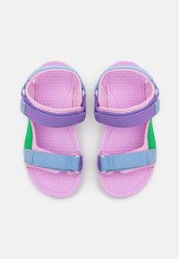 Sandalias moradas y rosas con correas ajustables en azul y verde. Suela texturizada con pequeños puntos para mayor agarre. Diseño ligero.