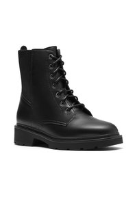 Botín de combate negro con cordones y suela gruesa, parte frontal en cuero liso y panel de tela elástica en el lateral, en ángulo para mostrar el lado exterior.