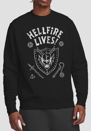 Man wearing black sweatshirt with white graphic of horned skull on shield, swords, dice, mace, and text "HELLFIRE LIVES!"