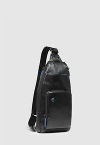 Borsa a tracolla in pelle nera con una texture liscia, caratterizzata da una tasca frontale, cerniere blu a contrasto e una tracolla regolabile.