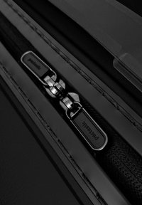 Nahaufnahme eines schwarzen Reißverschlusses mit zwei Metall-Zippern an einer strukturierten Tasche oder einem Etui, das detaillierte Nahtlinien und glatte Oberflächen zeigt.
