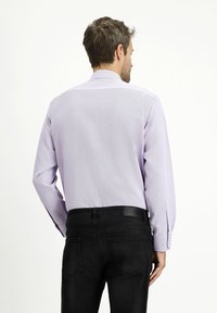 Camicia a maniche lunghe viola chiaro con tessuto testurizzato, caratterizzata da bottoni ai polsini, indossata con jeans neri. Vista posteriore mostrata.