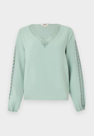 Ανοιχτό πράσινο μακρυμάνικο μπλουζάκι με V-λαιμόκοψη και δαντέλα κατά μήκος της λαιμόκοψης και στις δύο μανίκες.