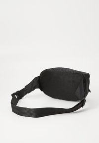 Sacoche en nylon noire avec un panneau en maille, de forme rectangulaire, bandoulière ajustable et texture douce. Dispose d'une boucle latérale pour une fermeture sécurisée.
