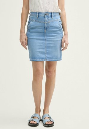 Light blue denim skirt with a fitted shape, high waist, front pockets, and subtle stitching detail. Worn with blue slip-on sandals.