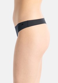 Svart stringtrosor i ett mjukt och stretchigt material. Har en minimalistisk design och en liten logotyp på vänster sida.