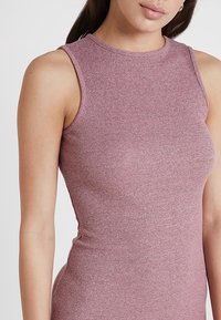 Haut sans manches à côtes en rose poussiéreux, design ajusté, encolure ronde, texture lisse, coutures minimales pour une finition propre.